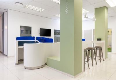 Bright breakout area with a high-top counter, stools, and green structural pillars.