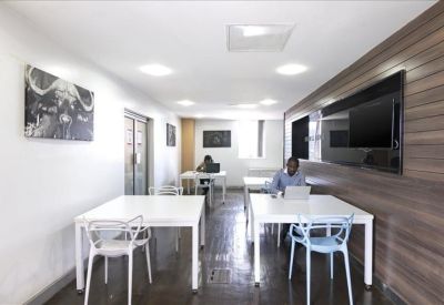 Bright coworking space with white desks, blue chairs, and wood paneling.