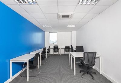 Open-plan workspace with rows of white desks and a bright blue wall.