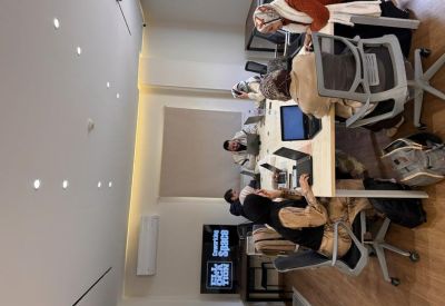 Bright shared workspace with professionals collaborating around a large light-wood table.
