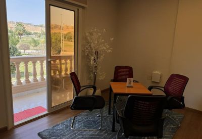 Small meeting area by a balcony with red chairs and a patterned rug.