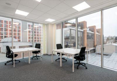 Bright corner office with white desks and floor-to-ceiling windows.
