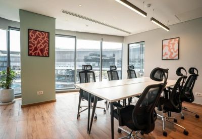 Shared workspace with white desks, black mesh chairs, and abstract red wall art.