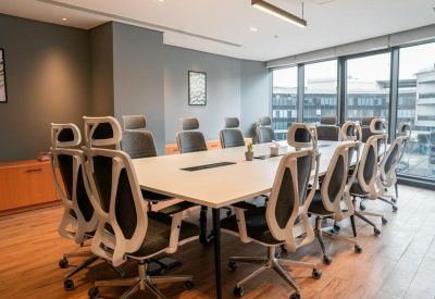 Spacious boardroom with a large white table, ergonomic white-framed chairs, and city views.