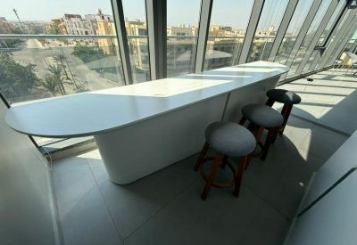 Curved white breakfast bar with gray stools overlooking large glass windows.