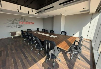 Professional boardroom with a long wood-finish table and gray mesh chairs.