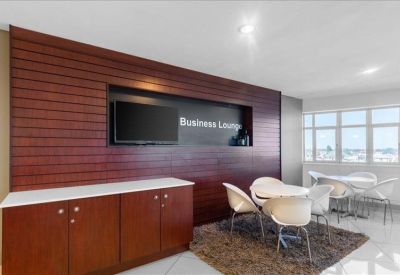 Modern business lounge featuring a wood-paneled feature wall and white armchairs.