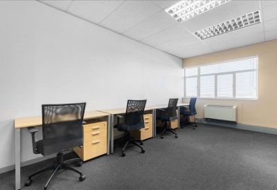 Bright shared office space with four workstations and large windows.