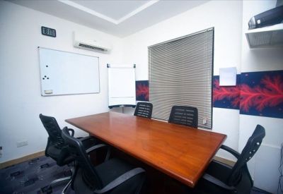 Meeting room featuring a wooden table, black chairs, and a whiteboard.