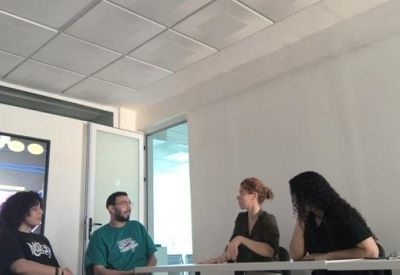 Four people sitting at a table during a meeting in a well-lit office space.
