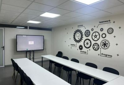 Bright conference room with long white tables and gear-themed wall art.