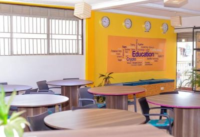 Bright communal workspace with round wooden tables, purple accents, and a yellow feature wall.