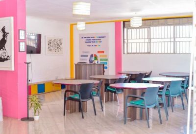 Meeting area with several round tables, blue chairs, and vibrant pink pillars under warm lighting.