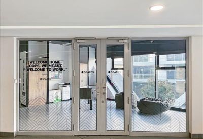 Glass entrance doors leading to an indoor breakout area with bean bag chairs.
