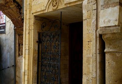 Traditional stone arched entrance with a decorative black wrought iron gate.