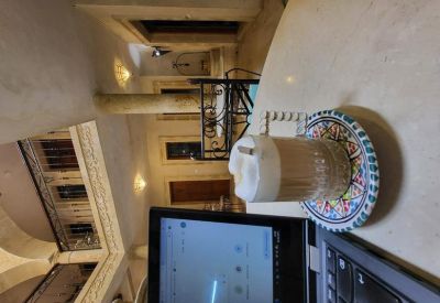 A coffee glass on a colorful saucer next to a laptop in a traditional indoor setting.