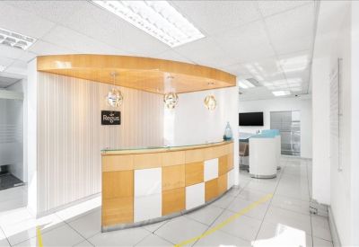 Bright reception area featuring a wood-panelled curved desk and checkerboard pattern.