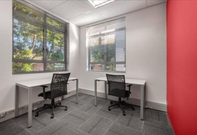 Private office suite with two white desks and a vibrant red accent wall.