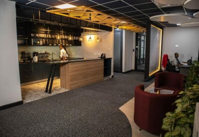Modern communal kitchen and breakout area with a wooden breakfast bar and warm lighting.