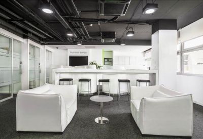 Spacious communal lounge with white armchairs, breakfast bar, and industrial ceiling.