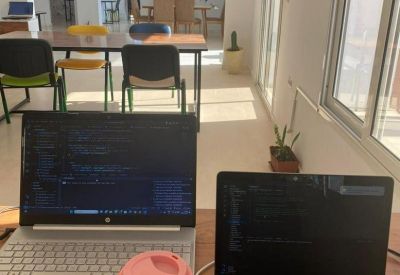 Open-plan coworking area with long tables and laptops.