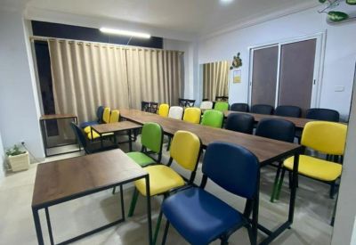 Training or meeting room with rows of colorful chairs and wooden tables.
