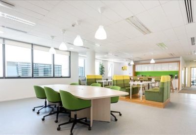 Spacious open-plan coworking area with green seating and modern pendant lighting.