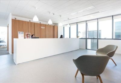 Clean, bright reception area with a long white desk and comfortable grey lounge chairs.