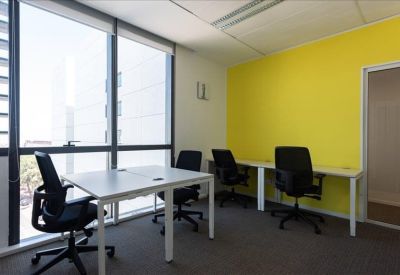 Private office space with a bright yellow feature wall and four workstations.