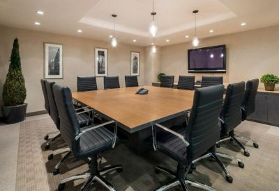 Large professional boardroom with a wooden table, black leather chairs, and recessed lighting.
