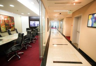 A long, bright hallway with polished floors leading to glass-walled meeting rooms.