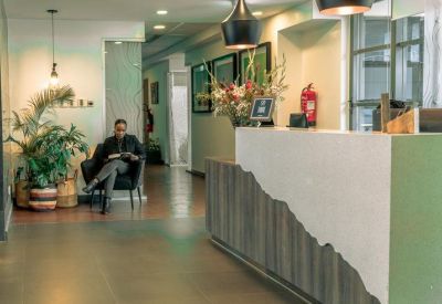 Professional reception area with a minimalist stone desk, stylish pendant lights, and greenery.