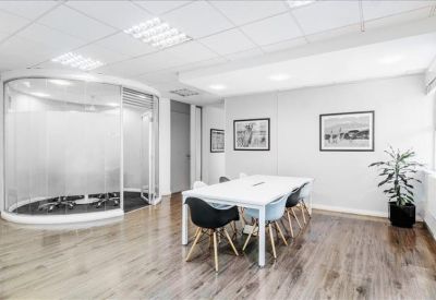Communal breakout area featuring a white table, modern seating, and potted plants.