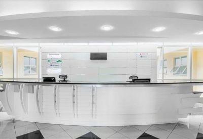 Modern white reception desk with curved details and bright overhead lighting.