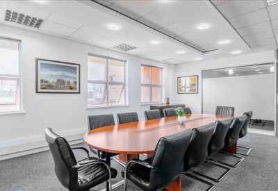 Professional boardroom with a large wooden table and black leather chairs.