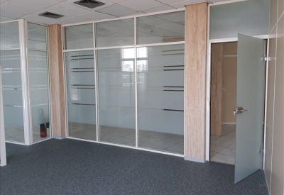 Private office space featuring frosted glass walls and dark grey carpeting.