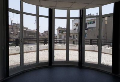 Spacious meeting area with a curved glass wall offering views of the city skyline.