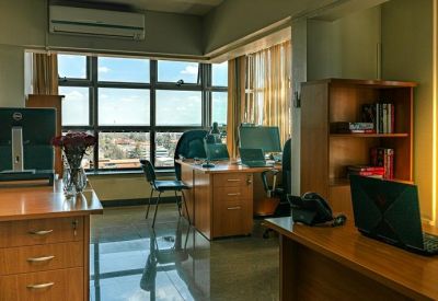 Private office suite with wooden desks, a bookcase, and city views.