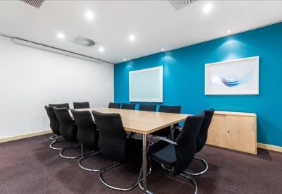 Professional boardroom with a long wooden table, black leather chairs, and teal feature wall.