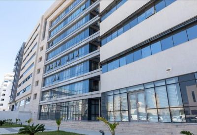 Modern multi-story office building facade with large glass windows and light stone cladding.