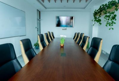 Professional meeting room with a long wood table, black leather chairs, and wall-mounted TV.