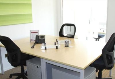 Interior office space with light wood desks and a green accent wall.