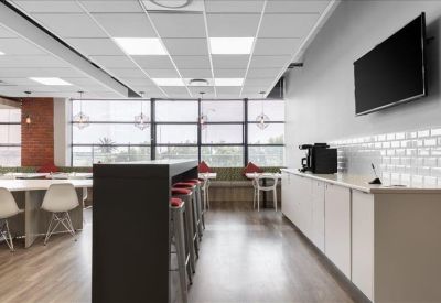 Communal kitchen and break area with white cabinetry and a breakfast bar.