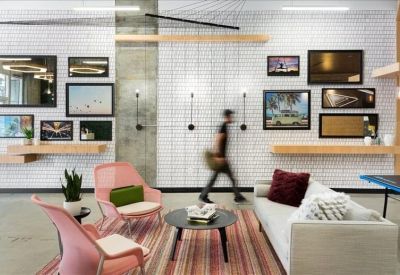 Modern lounge area with pink chairs, a striped rug, and a gallery wall of framed art.