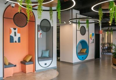 Vibrant breakout area featuring orange and blue arched seating nooks with cushions.