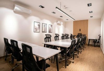 Long conference room with multiple black mesh chairs and a white table.
