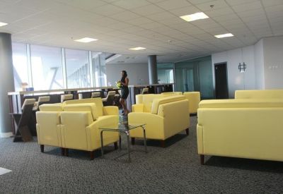 Spacious airport lounge with yellow leather armchairs and floor-to-ceiling windows.