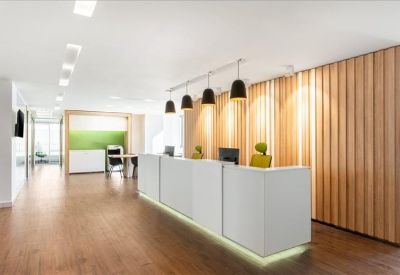 Bright reception area featuring a white desk, wood-slat wall, and pendant lighting.