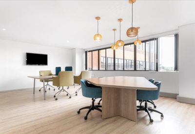Open-plan coworking area with modern pendant lights and blue and gold chairs.