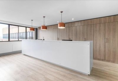 Minimalist white reception desk set against a warm wood-paneled feature wall.